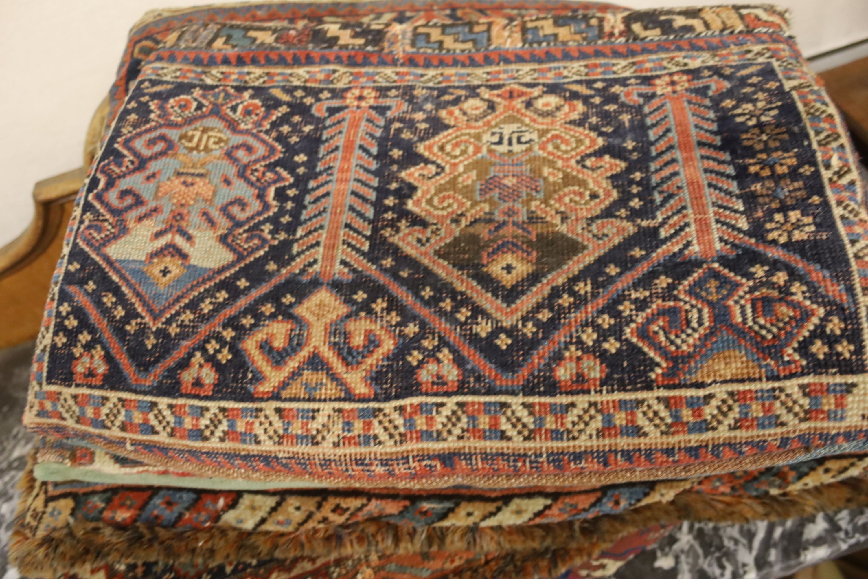 Three Bokhara rugs, four kilim-faced cushions and a small saddlebag, largest 74 x 50cm